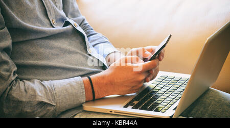 Young man looking at his smart phone, closeup on the hands Stock Photo