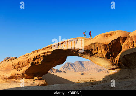 Couple hiking at Rock-Arch named Al Kharza, Wadi Rum, Jordan Stock Photo