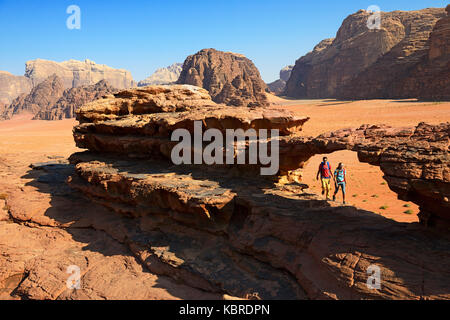 Couple hiking at Rock Arch, Al Borg Alsagheer, Wadi Rum, Jordan Stock Photo