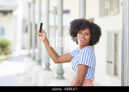 Portrait of afro american woman taking selfie by mobile laughing Stock Photo