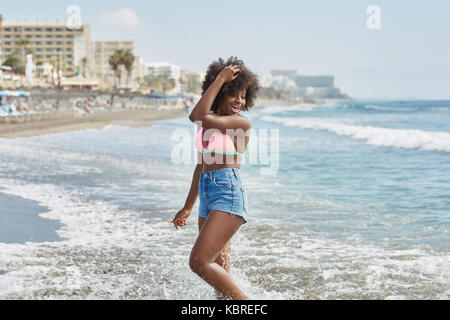 Portrait of pretty afro american girl standing in sea holding hand on head Stock Photo