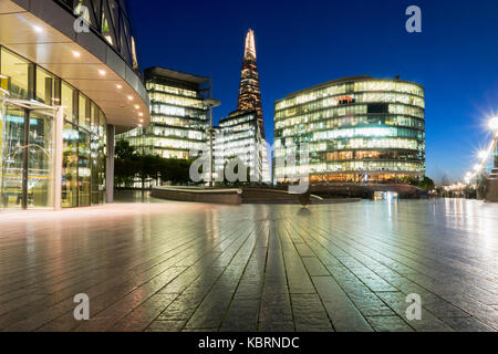UK, London, low angle view of modern office buildings in More London lit up at night with the Shard behind Stock Photo