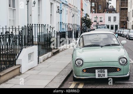 Pastel blue Nissan Figaro next to pastel houses in Notting Hill, London. Nissan Figaro was built for a short period (1991) purely for Japanese market. Stock Photo