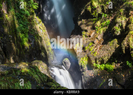 Close up of the flowing waters of Aira Force waterfall in the English Lake District, Cumbria, England, UK. Droplets in the air creating a rainbow. Stock Photo