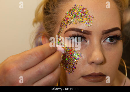Olympia Beauty Show: 1 October, 2017 London UK:  A young woman having glitter facepaint applied.  Credit: Steve Parkins/Alamy Live News Stock Photo