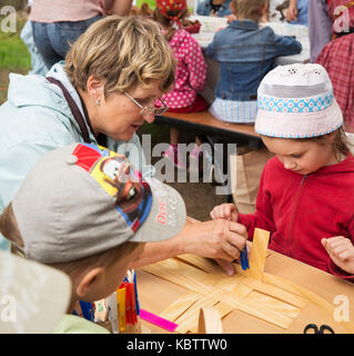ST. PETERSBURG, RUSSIA - JULY 26, 2015: Unidentified girl learns to weave bast basket on a city fair. Master class teaching children folk crafts weavi Stock Photo