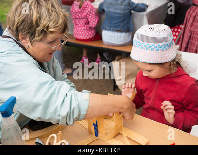 ST. PETERSBURG, RUSSIA - JULY 26, 2015: Unidentified girl learns to weave bast basket on a city fair. Master class teaching children folk crafts weavi Stock Photo
