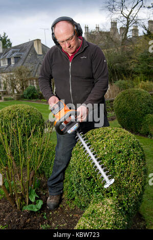 Andrew Tolman testing the Stihl HSA 56 hedgetrimmer at The Coach House, Ampney Crucis, Gloucestershire. Stock Photo