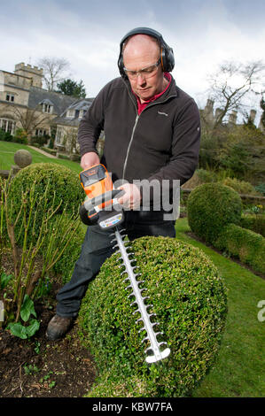 Andrew Tolman testing the Stihl HSA 56 hedgetrimmer at The Coach House, Ampney Crucis, Gloucestershire. Stock Photo