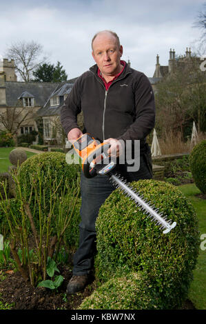 Andrew Tolman testing the Stihl HSA 56 hedgetrimmer at The Coach House, Ampney Crucis, Gloucestershire. Stock Photo