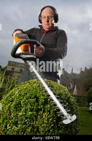 Andrew Tolman testing the Stihl HSA 56 hedgetrimmer at The Coach House, Ampney Crucis, Gloucestershire. Stock Photo