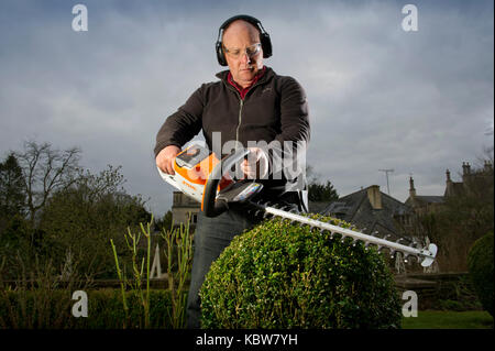 Andrew Tolman testing the Stihl HSA 56 hedgetrimmer at The Coach House, Ampney Crucis, Gloucestershire. Stock Photo