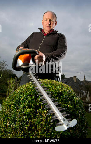 Andrew Tolman testing the Stihl HSA 56 hedgetrimmer at The Coach House, Ampney Crucis, Gloucestershire. Stock Photo