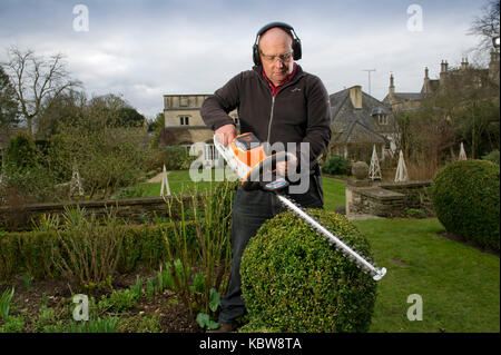 Andrew Tolman testing the Stihl HSA 56 hedgetrimmer at The Coach House, Ampney Crucis, Gloucestershire. Stock Photo