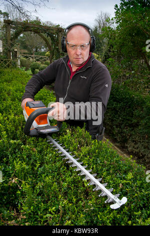 Andrew Tolman testing the Stihl HSA 56 hedgetrimmer at The Coach House, Ampney Crucis, Gloucestershire. Stock Photo