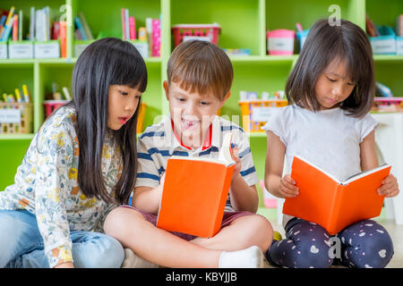 Children sitting on floor and reading tale book  in preschool library,Kindergarten school education concept Stock Photo