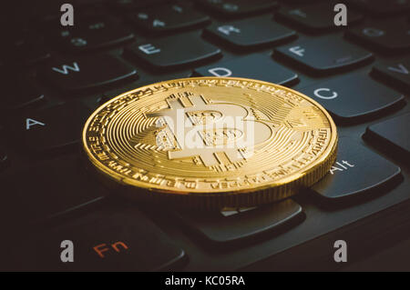 Golden bitcoins on a black computer keyboard. The electronic coin currency close up on the keys of a black keyboard Stock Photo