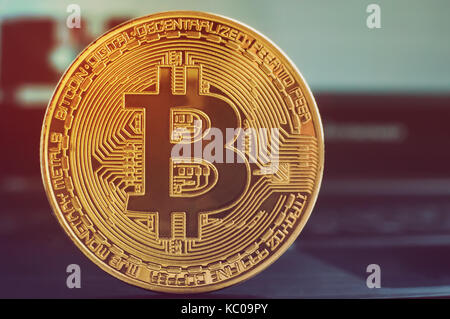 Cryptocurrency physical gold bitcoin coin on the black computer keyboard. Stock Photo