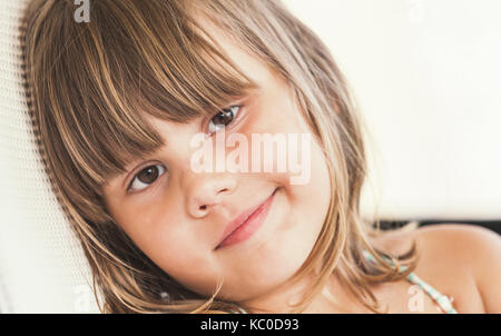 Slightly smiling Caucasian little girl, close up face portrait Stock Photo