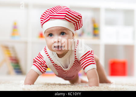 Six months old baby girl crawling on fluffy floor in nursery Stock Photo