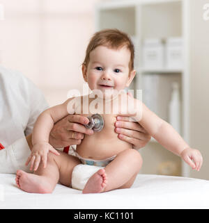Smiling baby at the doctor getting breath check up with stethoscope Stock Photo