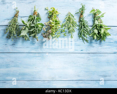 Different bunches of fresh herbs on the blue wooden background. Stock Photo