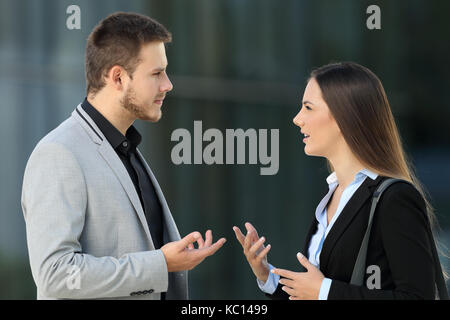 Side view portrait of two executives talking seriously standing outdoors on the street Stock Photo