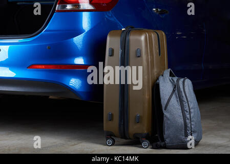 Baggage bags loading to car trunk close-up. Loading luggage in modern blue car Stock Photo
