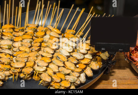 Appetizing cooked mussels on skewers at food festival, food and beverage concept Stock Photo