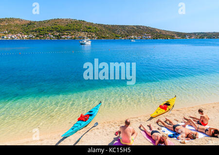ROGOZNICA, CROATIA - SEP 4, 2017: tourists relaxing on beautiful beach and two colorful kayaks on shore in Rogoznica town, Dalmatia, Croatia. Stock Photo