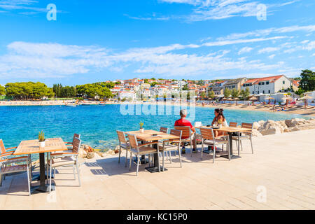 PRIMOSTEN, CROATIA - SEP 5, 2017: Couple of tourists sitting in seaside bar in Primosten town enjoying summer vacation, Dalmatia, Croatia. Stock Photo
