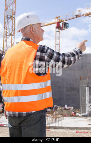senior builder in hardhats pointing outdoors Stock Photo