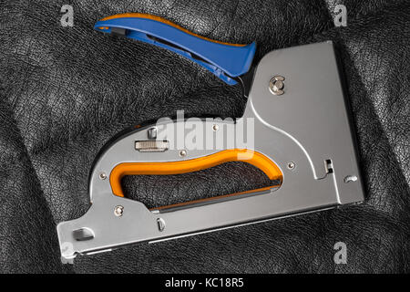 Construction stapler on a leather couch Stock Photo