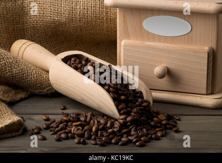 Coffee beans in wooden scoop with wooden coffee bean grinder on dark wooden table background Stock Photo