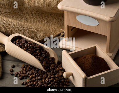 Coffee beans in wooden scoop and ground coffee in wooden scoop with coffee bean grinder on dark wooden table background Stock Photo