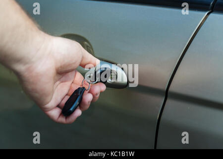 man's hand opens the car door with a key. Stock Photo