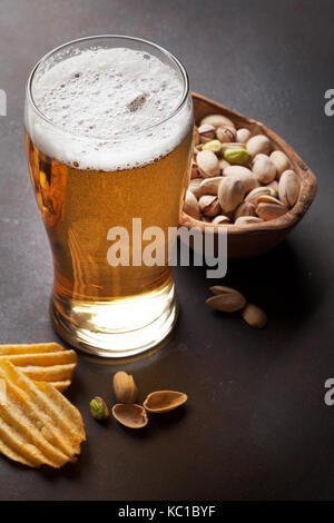Lager beer and snacks on stone table. Nuts, chips Stock Photo
