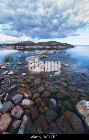 Lakeside photo taken at early morning at Ladoga skerries, Karelia region, Russia. Severe cloudy sky of this northen landscape is accompanied by harsh  Stock Photo