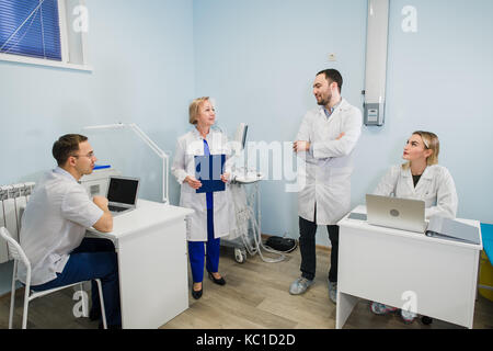 Group Of Doctors Involved In Serious Discussion With Medical Records Stock Photo