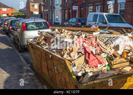 a full builders skip in a residential street, the north of england, Stock Photo