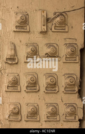 Four rows of doorbells line up across this wooden door frame in the French Quarter, New Orleans, Louisiana.  All painted over the same buff color. Stock Photo