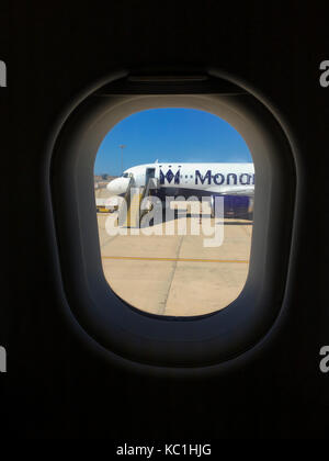 A deserted Monarch plane sits on the tarmac at Faro Airport, Portugal. Seen through the window of a neighbouring aircraft Stock Photo