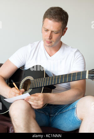 Handsome man compose a song on the guitar. Stock Photo