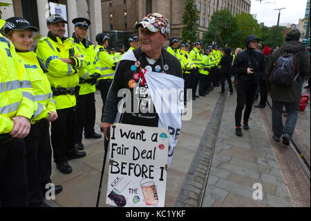 Manchester, UK. 1st October, 2017. Retired carpenter & joiner eighty-three-year-old Terry Hutt from Camden, London, walks a line of police officers near the Tory Party Conference Centre. Terry is an activist for DAN - Direct Action network. Ant-Fracking activists and dusabled anti Tory activists meet heavy police security at St Peter's Square near the Conference Centre. Pro-peace, anti-austerity, anti-war protests, including rallies, public meetings, comedy, music, & culture, take place during the four days of the Conservative Party Conference in Manchester, UK. 1st - 4th Oct 2017. The protes Stock Photo