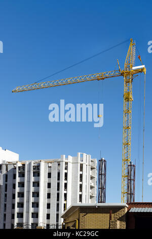 Building a new multi-storey house made of bricks with the help of a building crane. Stock Photo