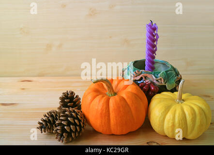 Minimalist Seasonal Decorations with Vibrant Color Ripe Pumpkins, Pine Cones and Purple Candle in Grape Motif Holder Stock Photo