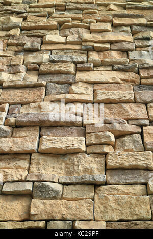Low angle of light brown and grey rough stone wall in the sunlight, vertical photo Stock Photo