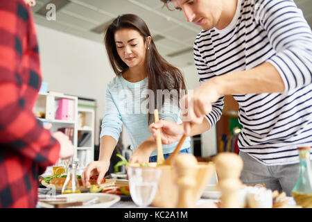 Portrait of beautiful Asian  woman preparing dinner with friends setting food on table for feasting celebration Stock Photo