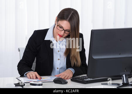 Young Businesswoman Analyzing Financial Report At Office Stock Photo