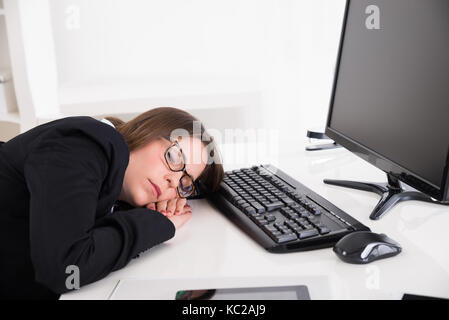 Young Businesswoman Sleeping On Desk In Office Stock Photo